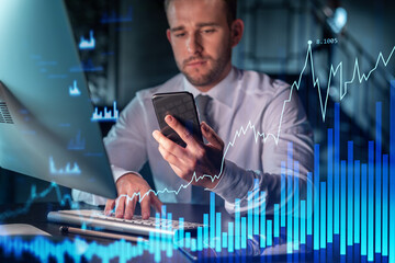 Businessman in casual wear using smart phone to optimize trading strategy at corporate finance fund. Forex chart hologram over modern office background at night time