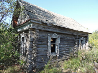 An old, uninhabited, wooden house with carved platbands on the windows, in an abandoned village.
