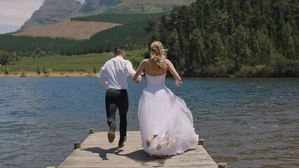 married couple jumping off jetty in lake bride and groom celebrating honeymoon sharing romantic wedding day - Powered by Adobe