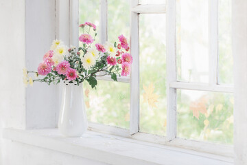 Fototapeta na wymiar chrysanthemums in vase on windowsill in autumn