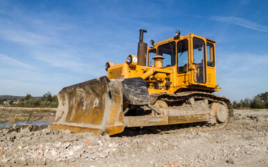 Obraz premium Large yellow bulldozer (dozer or crawler) on a construction site.