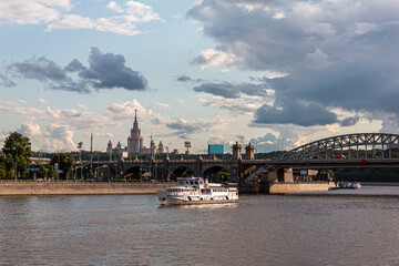 Fototapeta na wymiar River cruise ship sails along the Moscow river against the background of an old bridge