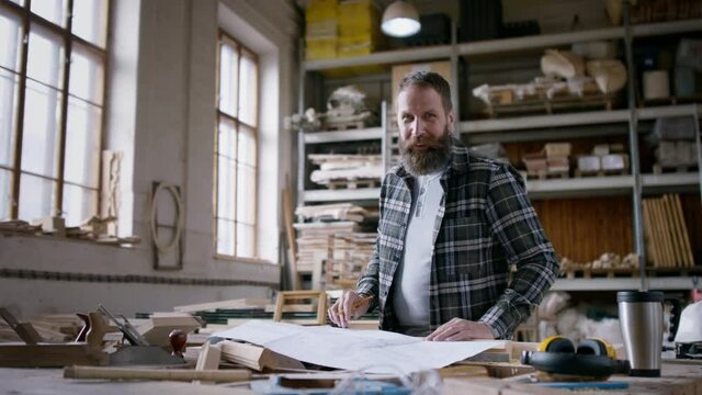 Male carpenter sketching desing of his product, looking at camera. Small business concept.