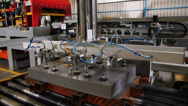 Manipulator with vacuum cups takes metal sheet to make detail for refrigerator at automatic production line in workshop