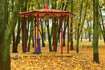 Autumn. City Park. Gazebo in the park and yellow leaves lying on the ground.