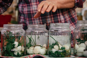 authentic photo of soiled female hands of elderly woman, cooking canned vegetables from harvest in kitchen, putting in glass jars