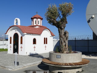 Place of rest in the hustle and bustle of the port: Small chapel and olive tree on the port area of...