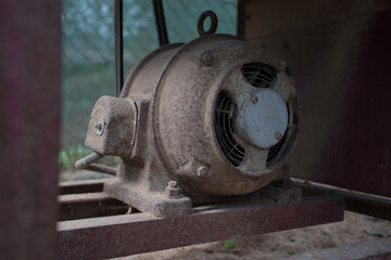 Old electric motor powering a table saw (bench saw). Vintage industrial equipment concept. Rusty and dirty electric engine power rotating machine