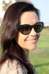 Joyful smiling young brunette woman wearing sunglasses