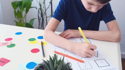 Close up Autism boy during therapy at home performs tasks for the development of the brain. Autism awareness concept. 4K, slow motion - Powered by Adobe