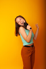 girl brunette teenager, 15 years holding a microphone in his hands depicting singing with his mouth open. The concept of postcards or a vocal lesson at school, back to school