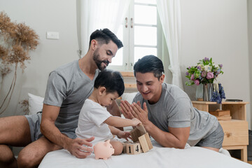 A couple gay parent playing with adopted child in bedroom