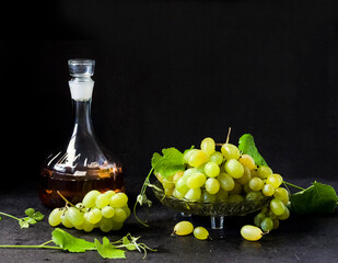 Fresh ripe grapes and decanter with grape juice on black background