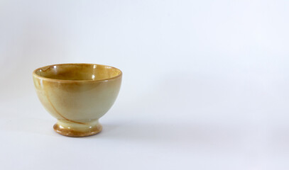 Light brown ceramic bowl varnished on white background. Selective focus. Copy space.