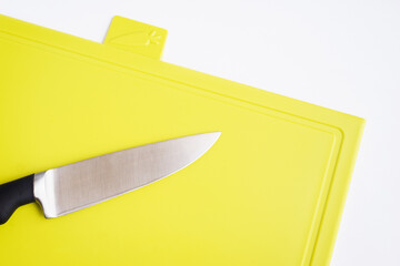 Bright green yellow clean plastic cutting board with a kitchen knife on a white background.