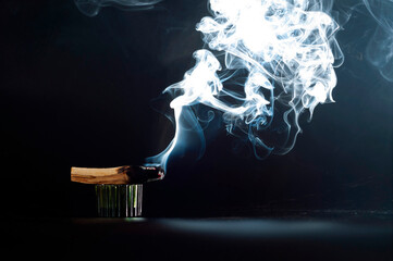 Palo santo incense stick on a black background. A sacred stick of wood burning with aromatic smoke. The concept of incense, healing, meditation, relaxation, cleansing the body and soul from stress.