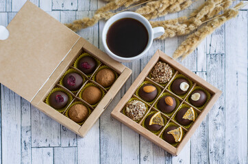 Handmade coffee chocolates in a porcelain cup of dried flowers on a gray wooden background.