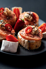 Open faced sandwiches stuffed fish, cream cheese, tomato, chili pepper and sesame seed. Smorrebrod traditional Danish sandwich, shallow focus, close up.