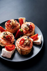 Open faced sandwiches stuffed fish, cream cheese, tomato, chili pepper and sesame seed. Smorrebrod traditional Danish sandwich, shallow focus, close up.
