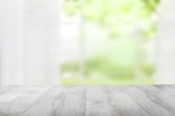 Empty rustic wooden bright table top in front of abstract blurred curtain window natural green background. Template for your product display montage. Space for design.