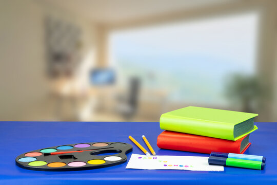 Colorful school equipment and two books on dark blue table against abstract blurred office background. Space for your text or dsiplay product montage.