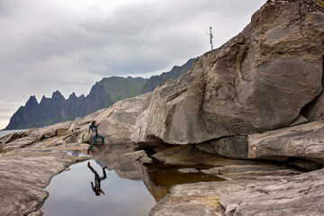 Child, having fun in Tungeneset, Senja, Norway, jumping over big puddle, making reflection in the water