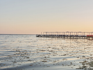 Obraz premium Evening sea. Empty pier, lots of algae and crimson sun.