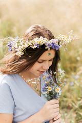 Naklejka premium Cute smiling little girl with flower wreath on the meadow. Portrait of adorable small kid outdoors.
