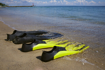 Two pairs of flippers lie on the seashore in the surf. Sunny day, Odessa Ukraine.