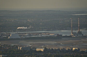 Fototapeta na wymiar Beautiful closeup aerial view of Dublin Waste to Energy (Covanta Plant), Poolbeg CCGT chimneys seen from Ticknock, Dublin, Ireland. Telephoto view of industrial cityscape. Soft and selective focus