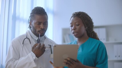 Nurse discussing patient's illness history with doctor using tablet, medical app