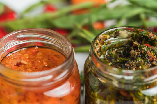 Selective focus on two jars with Rocoto and Chimichurri sauces.