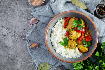 Spicy chicken curry with rice. Curry sauce with chicken and rice on gray background. Top view