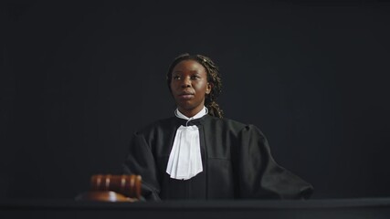 African female judge striking hammer, announcing end of proceeding at court