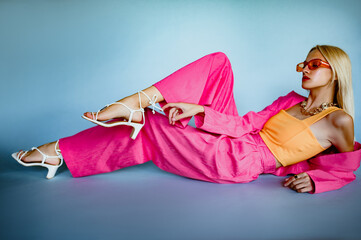 Full length fashion portrait of confident woman wearing trendy summer suit with pink fuchsia color blazer, wide leg trousers, orange top, stylish sunglasses, strappy white sandals. Copy, empty space