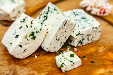 Slice of sheep cheese on a wooden background made from homemade fresh milk.