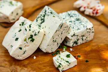 Slice of sheep cheese on a wooden background made from homemade fresh milk.
