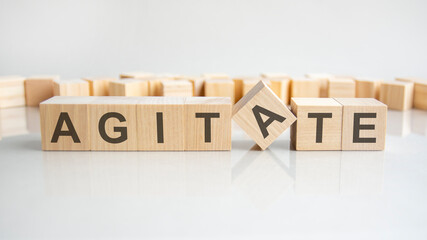 agitate text on a wooden blocks, gray background.