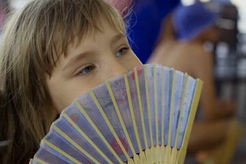 a five-year-old girl fanning herself with a fan