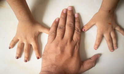 Indian Man's hand kept middle of kid's two hands on the floor for playing at home in Dhaka, Bangladesh