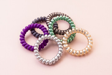 Group of colorful spiral rubber bands on pink background. Concept of healthy hair