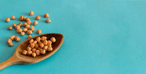 Wooden spoon with chickpeas on blue background. Top view. Flat lay. Copy space. Mediterranean food.