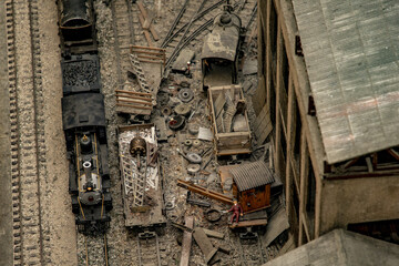 Overhead shot of a cluttered miniature train station with black locomotive train and carts