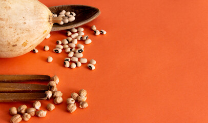 Beans with dried pumpkin, fork and wooden ladle on orange background. Flat lay. Copy space. Mediterranean food.