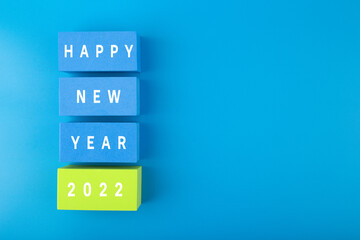 Happy New Year 2022 blue minimal trendy concept. Modern flat lay composition with blue toy blocks with written Happy New Year text on blue background with copy space