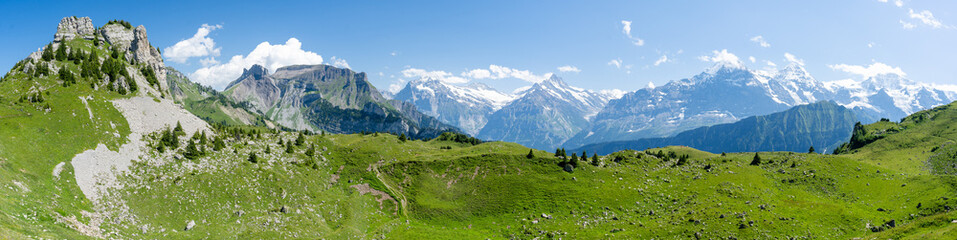 Fototapeta na wymiar Panorama sur une vallée verte devant une chaine de montagne 