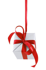 Hanging on a ribbon silver gift wrapped present with red satin bow isolated on white
