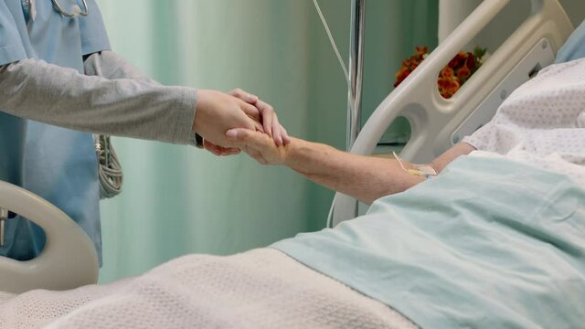 hospital nurse holding hand of old woman in bed comforting elderly patient hospitalized recovering from illness medical professional at bedside giving encouragement health care support