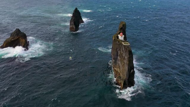 Remarkable aerial of the Pridrangaviti lighthouse perched on a remote rocky island in the Atlantic ocean off the coast of Iceland.