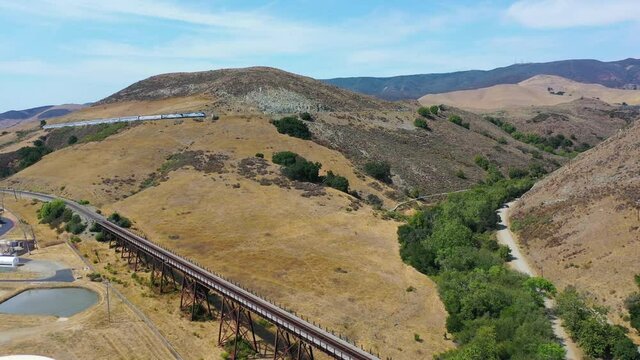 Excellent aerial rising shot of Amtrak passenger train ascending the Cuesta grade near San Luis Obispo, California.